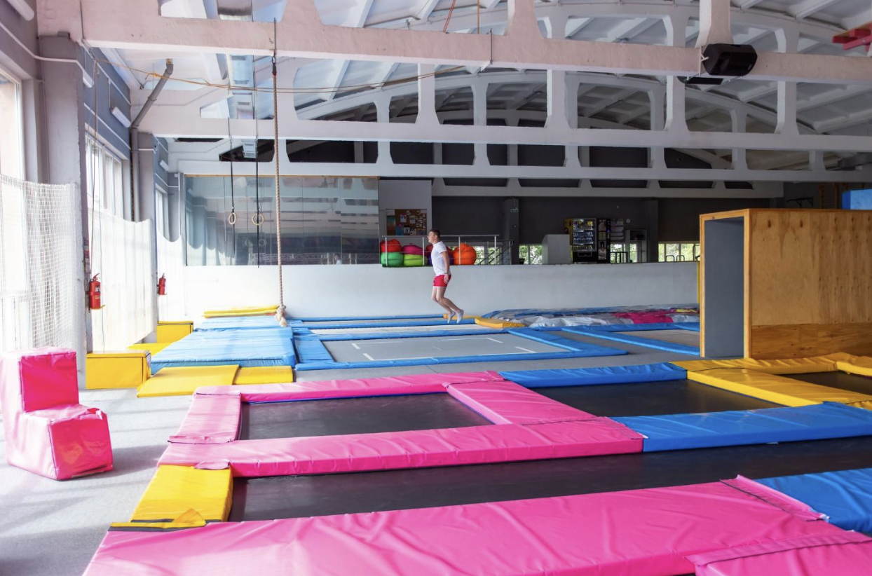 An indoor trampoline park with colorful safety mats and a person jumping, relevant to legal considerations when suing a trampoline park for injuries.