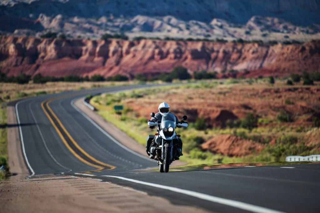 A motorcyclist riding on a scenic Arizona highway with red rock formations in the background, highlighting the importance of understanding Arizona's helmet laws for riders.