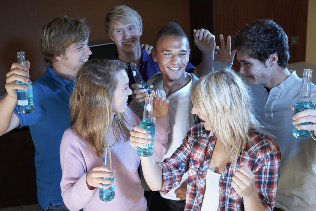 Group of teenagers socializing and holding clear bottles of blue liquid, depicting a social gathering that may relate to the legal topic of minors in possession of alcohol in Arizona.