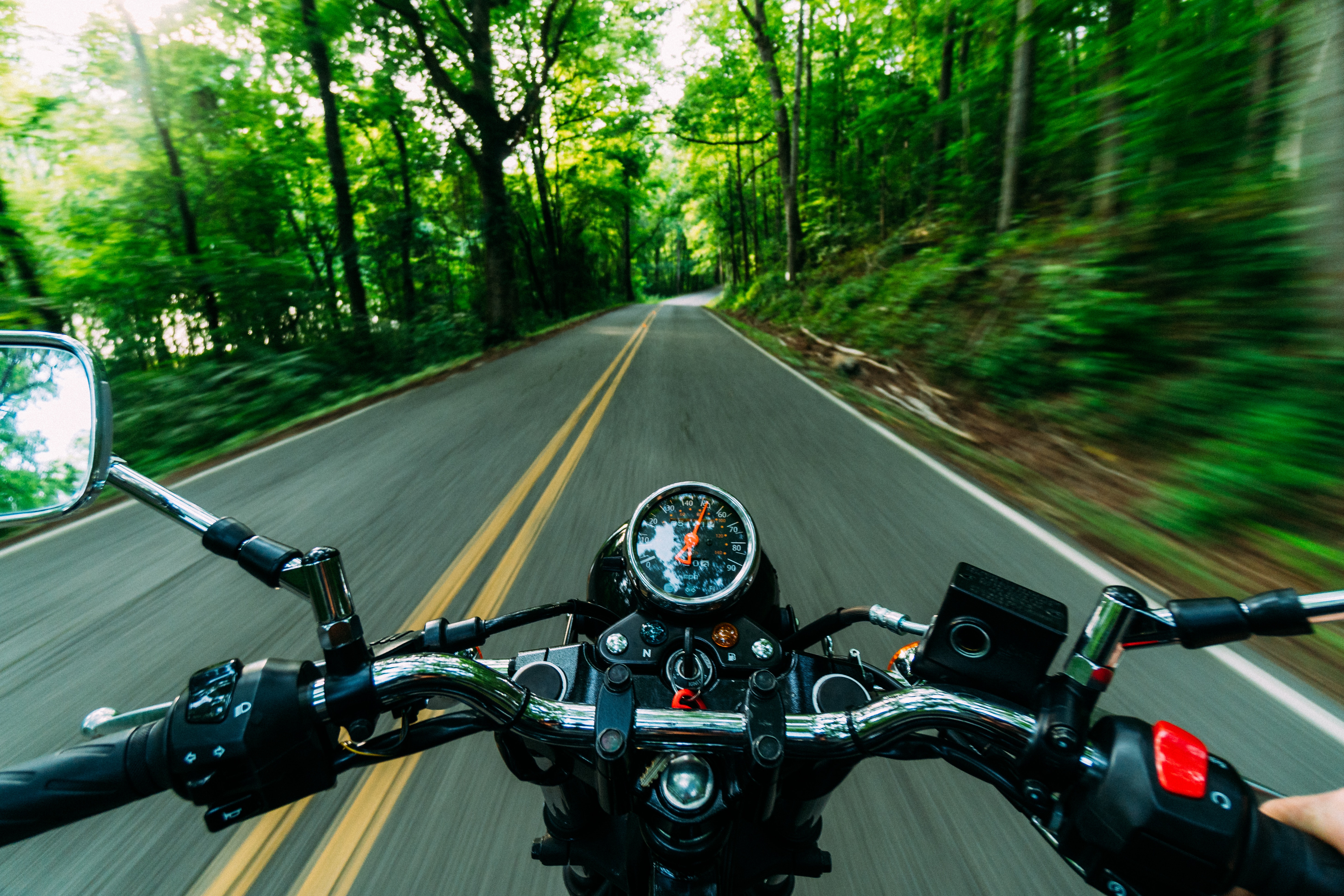 Rider's perspective of a motorcycle handlebar with a speedometer and a road ahead, symbolizing the experience of riding a motorcycle and the potential need for a motorcycle accident lawyer.