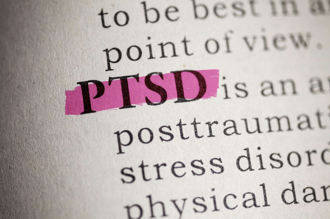 Close-up of the acronym 'PTSD' highlighted in pink on a page of text, discussing post-traumatic stress disorder, in the context of car accidents and their psychological impact.