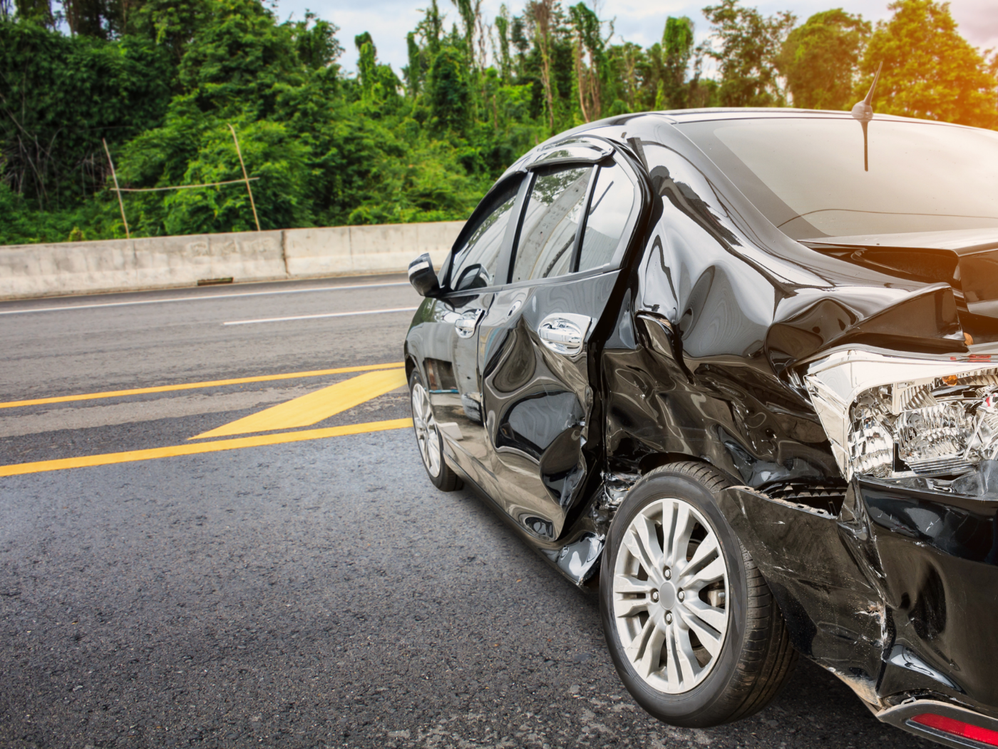 Damaged car with a crushed side panel on a road, depicting the aftermath of a vehicle collision which can often result in traumatic brain injuries.